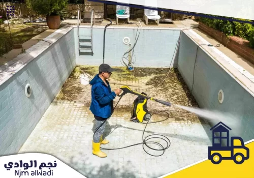 شركة تنظيف منازل بطريب 0541210318 نجم الوادي فني يقوم بإزالة الأوساخ من أرضية المسبح باستخدام ماكينة تنظيف ضغط الماء.