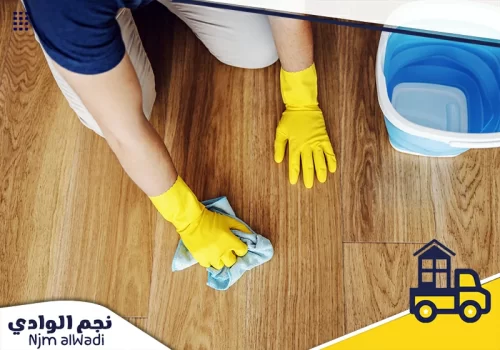 عملية تنظيف للأرضيات باستخدام قماش مبلل ودلو، مع اهتمام بالتفاصيل والنظافة.